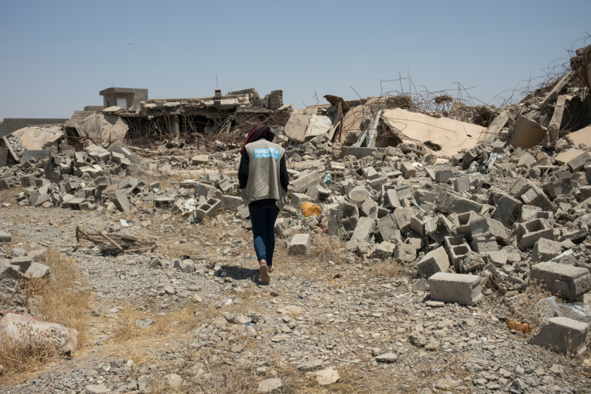 un homme de Handicap International marchant au milieu des décombres dans une ville bombardée en Irak